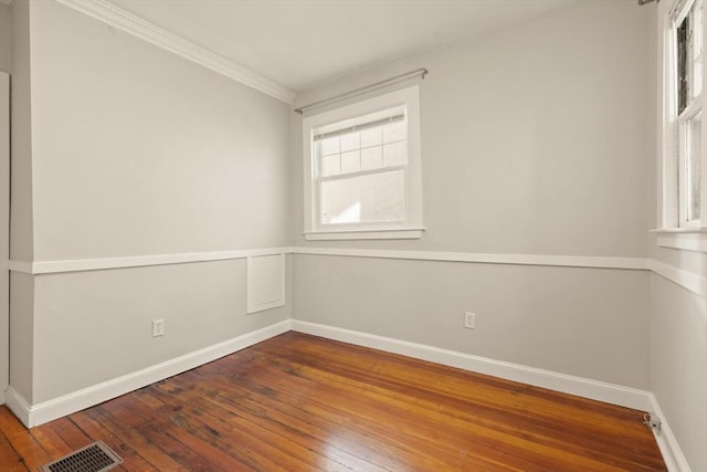 spare room with hardwood / wood-style floors, baseboards, healthy amount of natural light, and crown molding