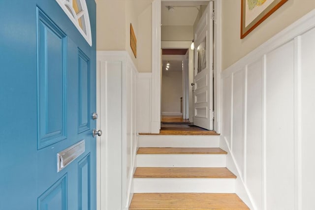 entrance foyer with a decorative wall, wainscoting, and stairway