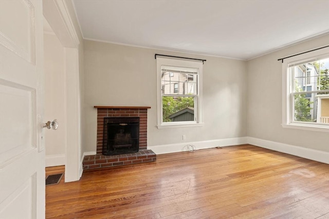 unfurnished living room with wood-type flooring, ornamental molding, baseboards, and a fireplace