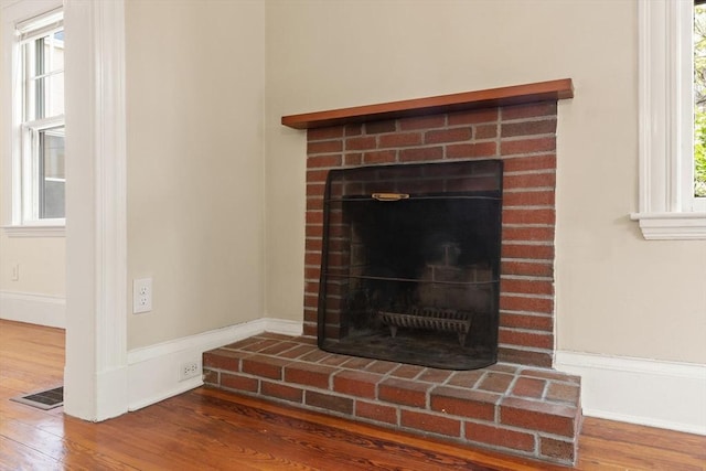 detailed view of wood finished floors, a fireplace, and baseboards