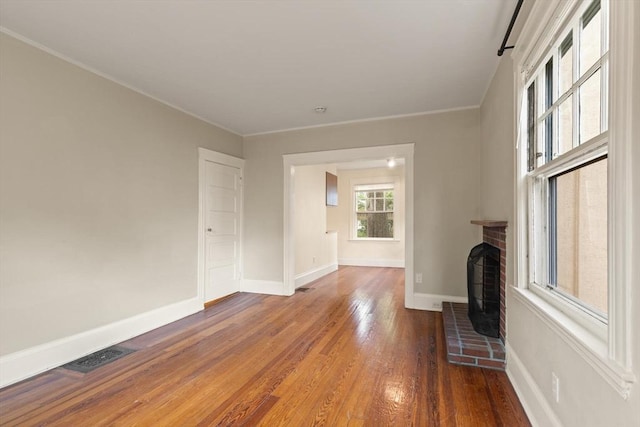 unfurnished living room with hardwood / wood-style floors, baseboards, and crown molding