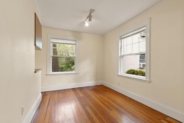 unfurnished room featuring baseboards, hardwood / wood-style flooring, and rail lighting