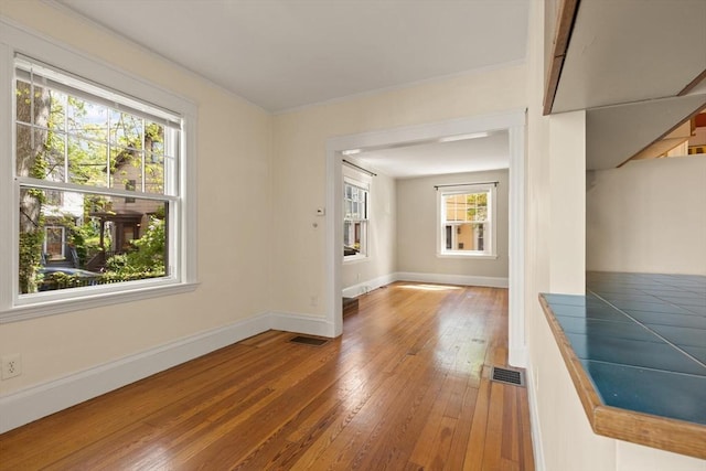 unfurnished living room with hardwood / wood-style flooring and baseboards