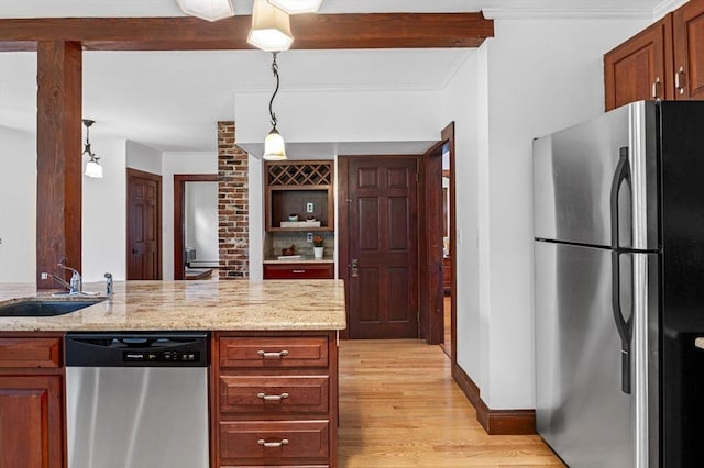 kitchen with appliances with stainless steel finishes, a sink, light stone counters, ornamental molding, and light wood-style flooring