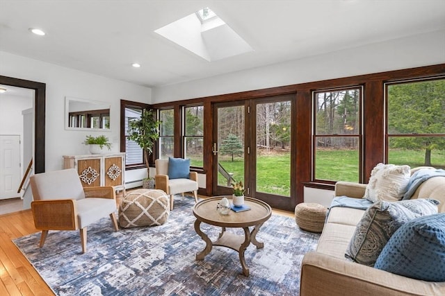 interior space with a skylight, a baseboard radiator, wood-type flooring, and recessed lighting