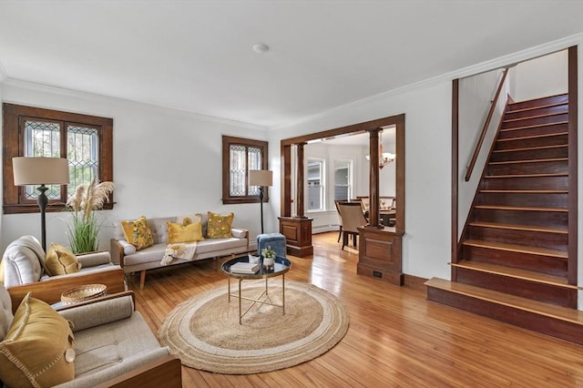living area featuring stairs, ornate columns, and ornamental molding