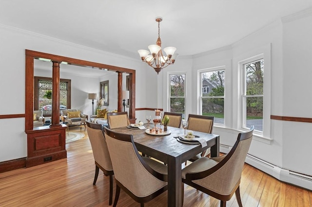dining area featuring light wood-type flooring, ornamental molding, ornate columns, and a notable chandelier