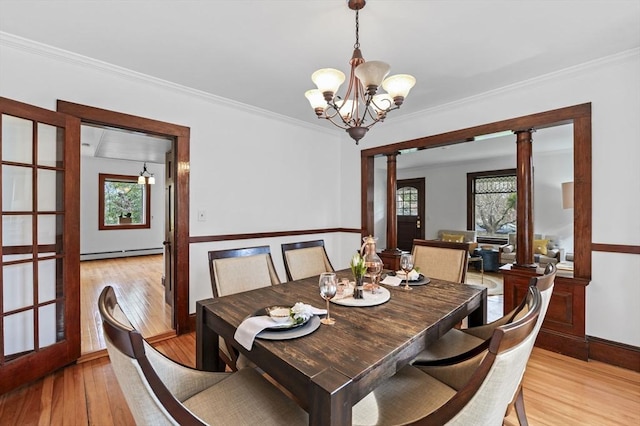 dining space featuring an inviting chandelier, a baseboard radiator, light wood-style flooring, and crown molding