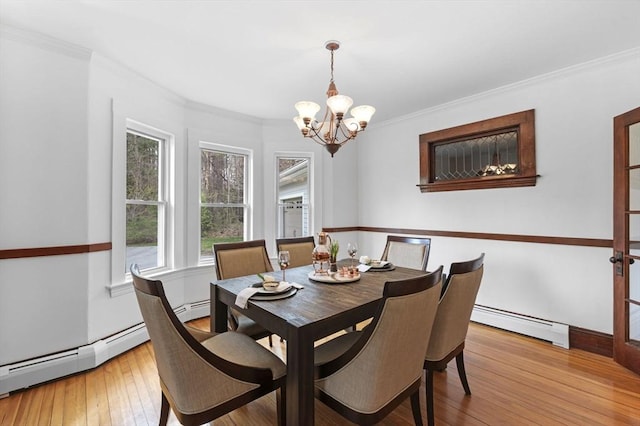 dining space featuring light wood-style floors, crown molding, a baseboard heating unit, and a notable chandelier