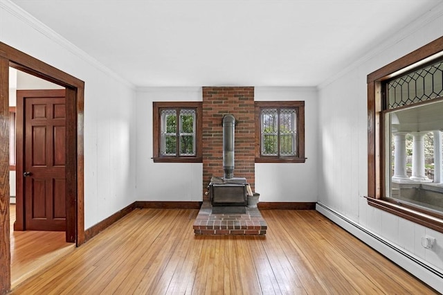 unfurnished living room with plenty of natural light, a wood stove, and a baseboard heating unit
