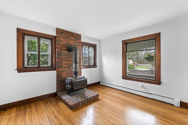 interior space featuring plenty of natural light, a wood stove, baseboards, and baseboard heating