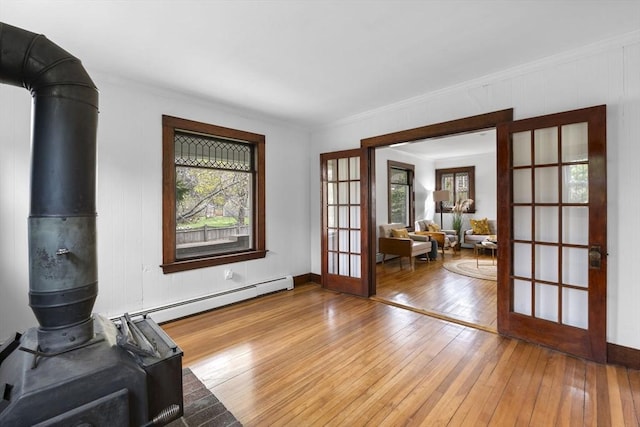 interior space featuring french doors, a wood stove, wood-type flooring, and a healthy amount of sunlight