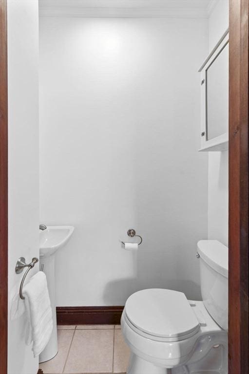 bathroom featuring crown molding, a sink, tile patterned floors, baseboards, and toilet