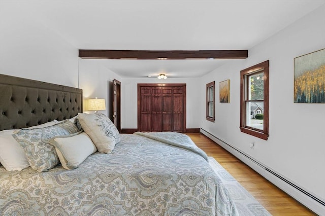 bedroom featuring baseboards, a baseboard radiator, beam ceiling, and wood finished floors