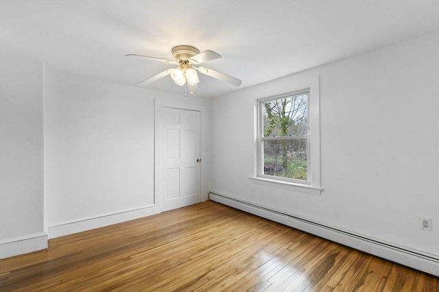 spare room featuring a ceiling fan, a baseboard heating unit, and light wood-style flooring