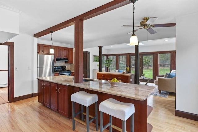 kitchen with a ceiling fan, hanging light fixtures, baseboards, light wood finished floors, and stainless steel appliances