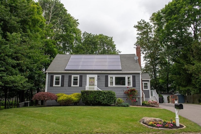 15 Lambert Ave, Stoughton, MA 02072 - view of front facade with a chimney, roof mounted solar panels, and a front lawn