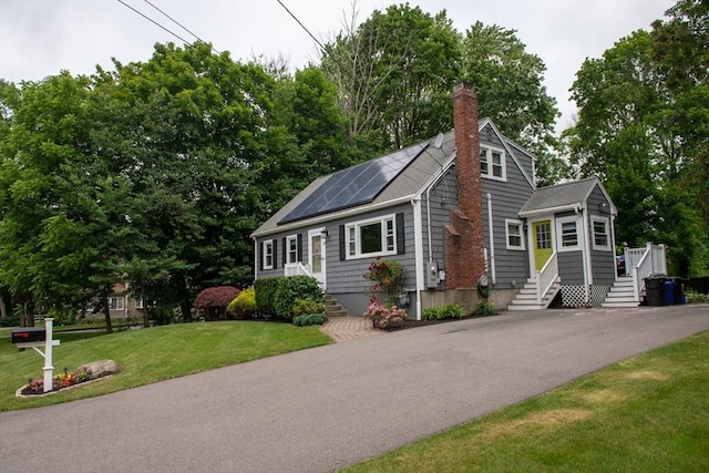 15 Lambert Ave, Stoughton, MA 02072 - view of front of property featuring a chimney, roof mounted solar panels, and a front lawn