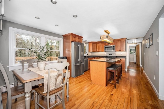380 New W Townsend Rd, Lunenburg, MA 01462 - kitchen with appliances with stainless steel finishes, a center island, light wood-style flooring, brown cabinetry, and recessed lighting