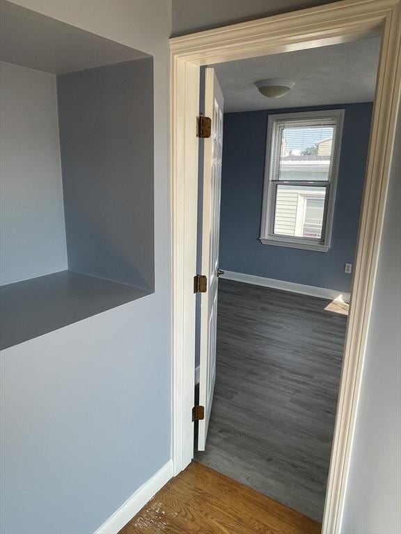 hall with baseboards and wood finished floors