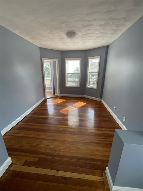 empty room with hardwood / wood-style flooring and baseboards