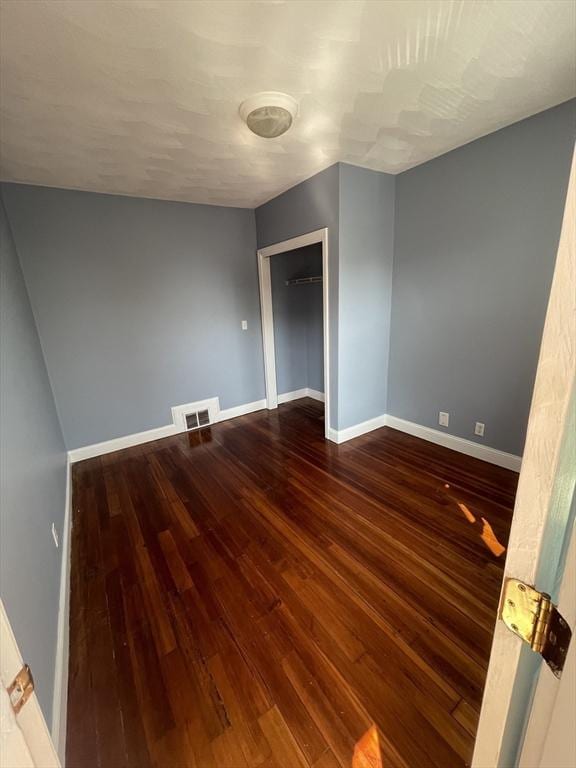 empty room with visible vents, baseboards, and wood finished floors