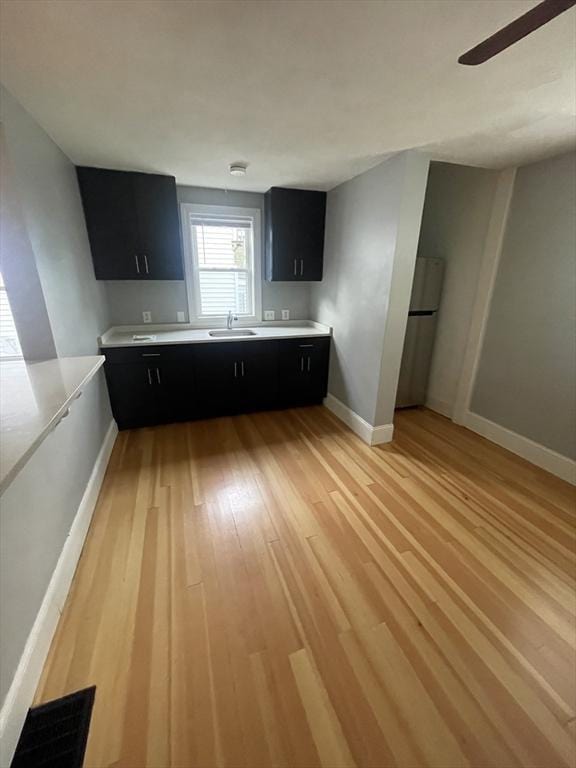 kitchen with light wood-style floors, dark cabinets, light countertops, and freestanding refrigerator