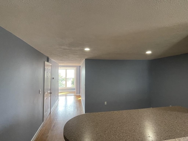 hall with recessed lighting, a textured ceiling, and wood finished floors