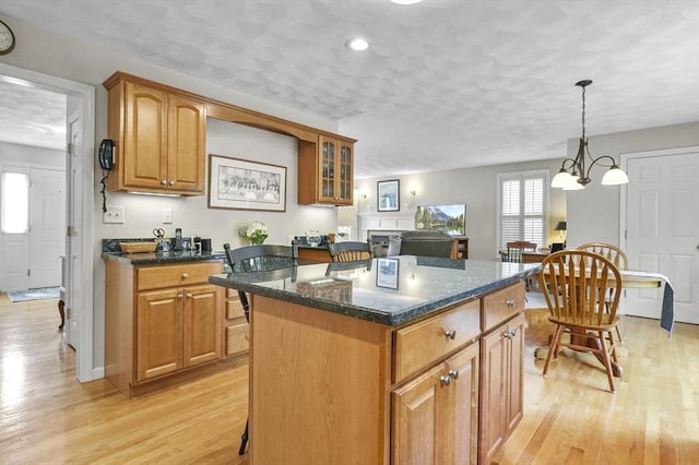 155 Burlington St, Woburn, MA 01801 - kitchen featuring light wood finished floors, a kitchen island, brown cabinetry, dark stone countertops, and recessed lighting