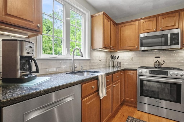 155 Burlington St, Woburn, MA 01801 - kitchen with stainless steel appliances, a sink, dark stone counters, brown cabinets, and light wood finished floors