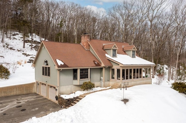 view of front of property featuring a garage, aphalt driveway, and a chimney