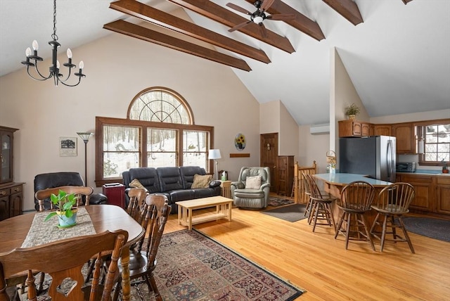 dining area featuring a wall unit AC, light wood finished floors, high vaulted ceiling, beamed ceiling, and ceiling fan with notable chandelier