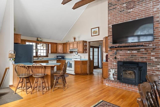 kitchen with brown cabinets, freestanding refrigerator, white electric range, under cabinet range hood, and a sink