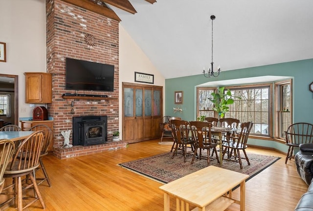 dining space with high vaulted ceiling, a notable chandelier, and light wood-style flooring