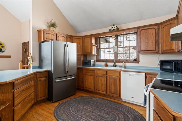 kitchen featuring brown cabinetry, freestanding refrigerator, black microwave, and white dishwasher