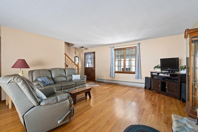 living room featuring a baseboard heating unit, light wood-style floors, and stairway