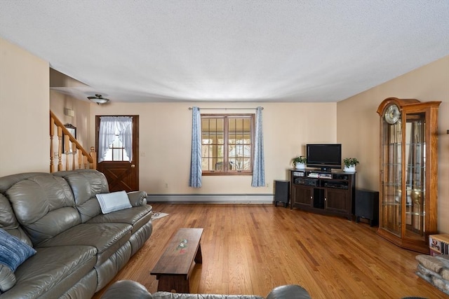 living area featuring stairway, baseboard heating, and wood finished floors