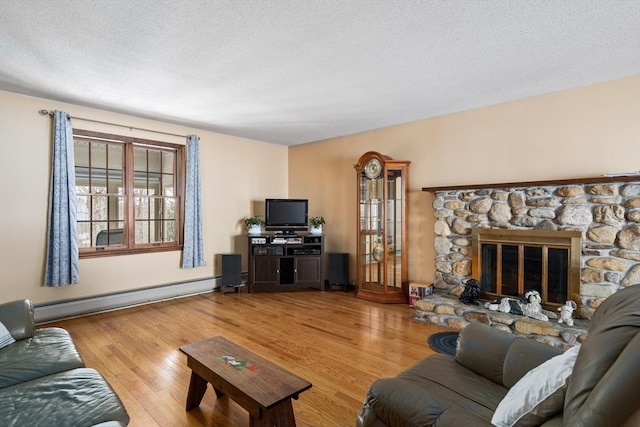 living area featuring a baseboard radiator, a fireplace, a textured ceiling, and wood finished floors