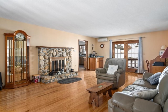 living room with an AC wall unit, a fireplace, and wood finished floors