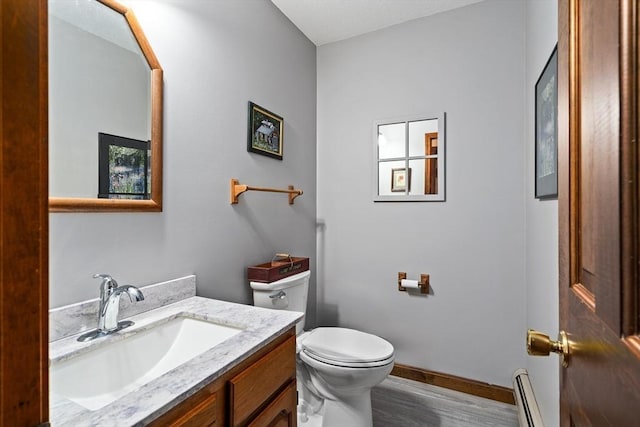 half bathroom with toilet, wood finished floors, vanity, baseboards, and baseboard heating