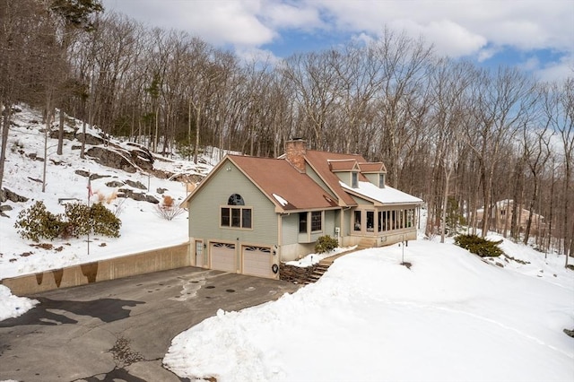 view of front of house with a garage, driveway, and a chimney