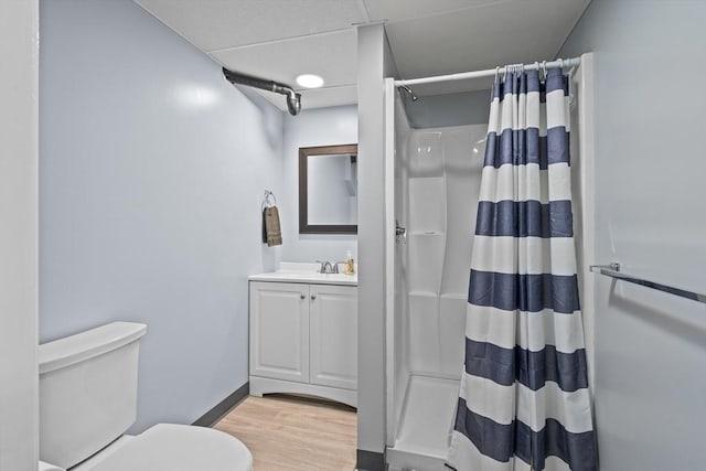 bathroom featuring toilet, wood finished floors, vanity, baseboards, and a shower with curtain