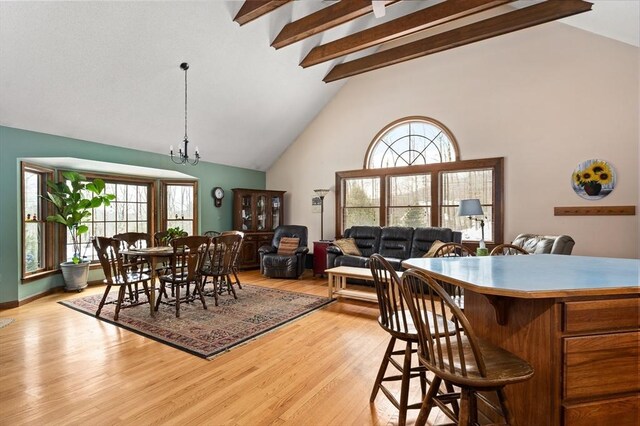 dining room featuring high vaulted ceiling, light wood-type flooring, a notable chandelier, and beamed ceiling