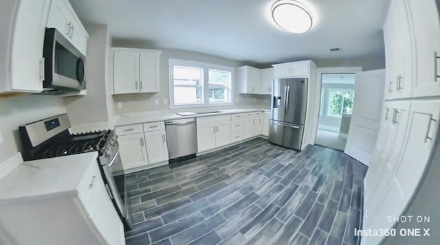 kitchen with white cabinets, stainless steel appliances, and dark hardwood / wood-style floors