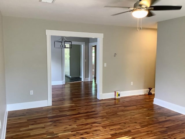 empty room with ceiling fan with notable chandelier and dark hardwood / wood-style floors