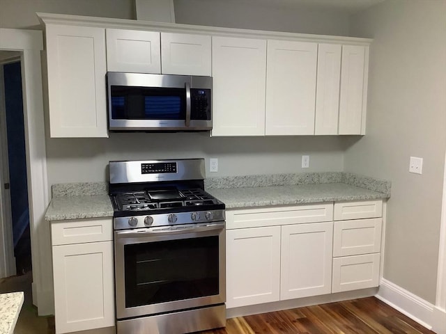 kitchen with appliances with stainless steel finishes, white cabinetry, and dark wood-type flooring