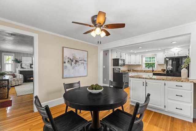 31 Webster St, Randolph, MA 02368 - dining area featuring ceiling fan, light wood finished floors, ornamental molding, baseboards, and a lit fireplace