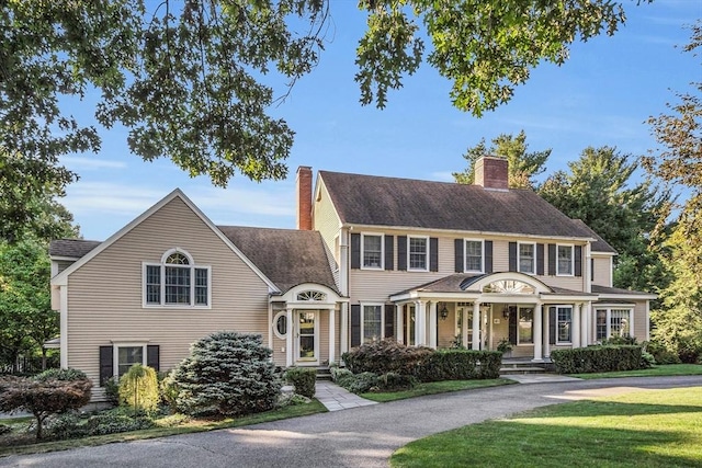 colonial-style house featuring a front lawn and a chimney