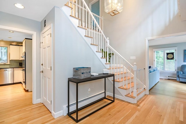 28 Smithshire Ests, Andover, MA 01810 - stairway with baseboard heating, wood finished floors, a towering ceiling, a chandelier, and recessed lighting