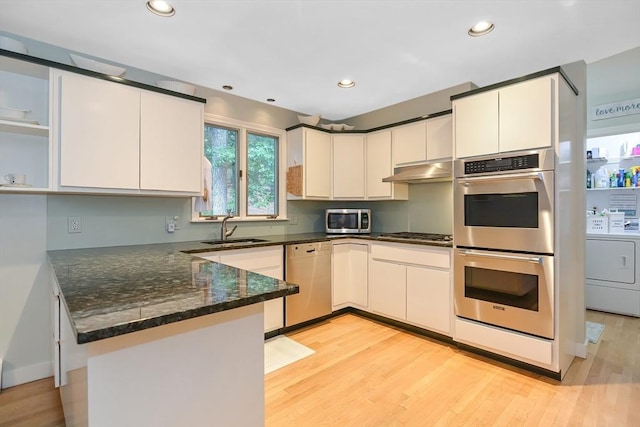 28 Smithshire Ests, Andover, MA 01810 - kitchen featuring stainless steel appliances, a peninsula, washer / clothes dryer, dark stone counters, and under cabinet range hood